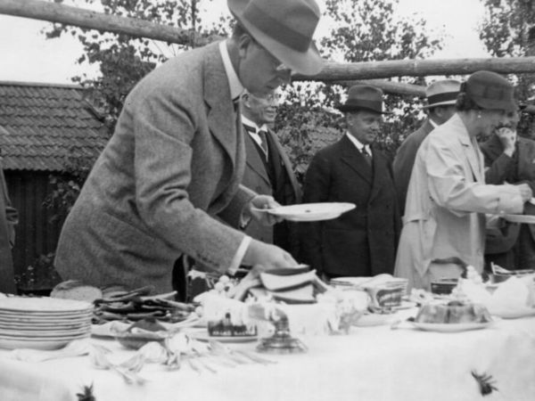 En man förser sig med godsaker från ett smörgåsbord. I bakgrunden syns fler människor som gör samma sak.