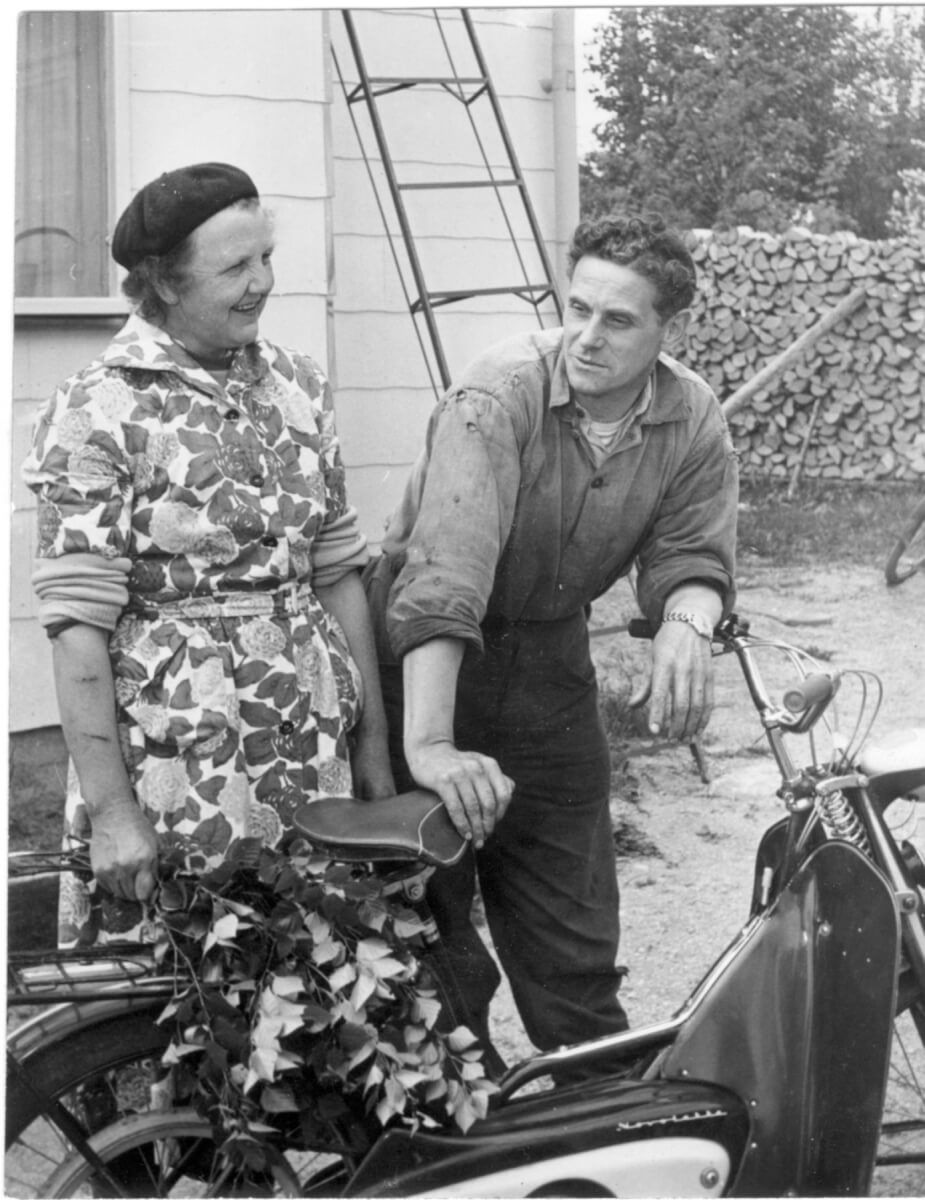 En man och en kvinna står bakom en moped.
