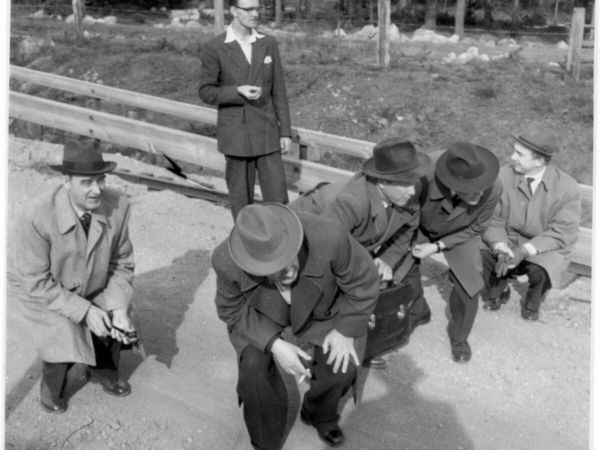 En grupp män går nedhukade längs en väg.