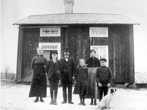 En familjebild tagen framför ett hus.