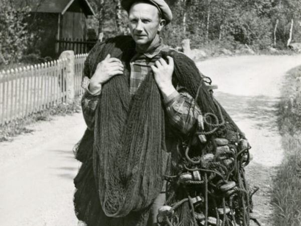 En fiskare bär nät med flöten och rep.