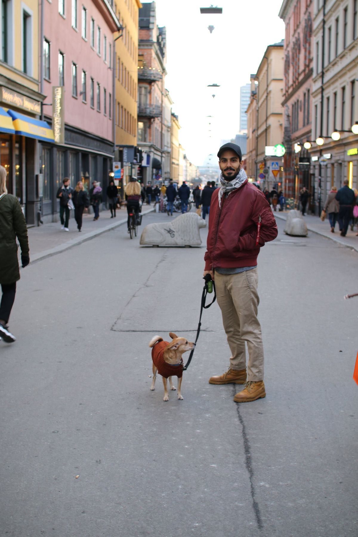 En man med hund står på gågata.