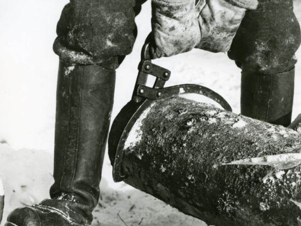 Någon håller i en timmersax som är fäst runt en stock.