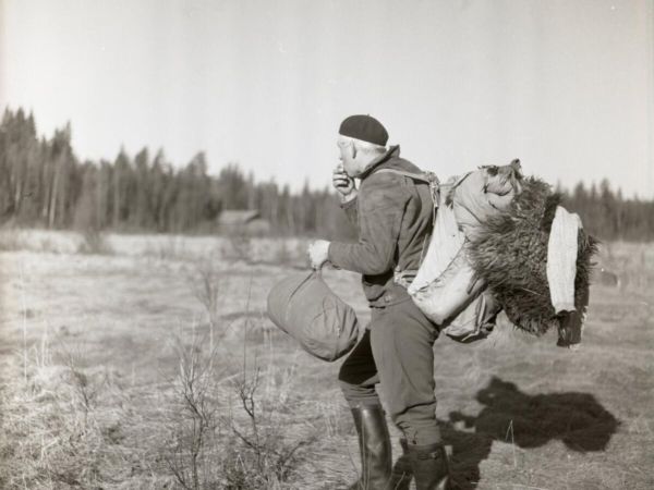 Med ena handens fingar vilandes på läpparna är mannen på väg bort från kameran. Mitt i ett steg har han förevigats på Degelmyren med sovsäcken i handen och packningen på ryggen. Han tittar mot skogslinjen som omgärdar myren och kliver med stövelklädda steg vidare mot nya äventyr.