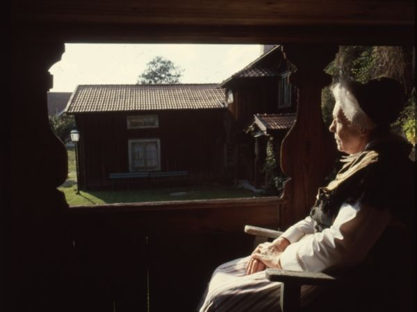 Kvinna sitter och tittar ut över gårdstun.