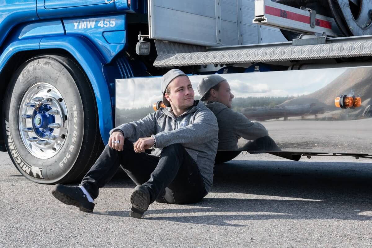Man sitter lutad mot lastbil.