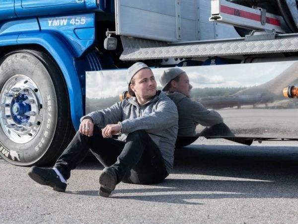 Man sitter lutad mot lastbil.