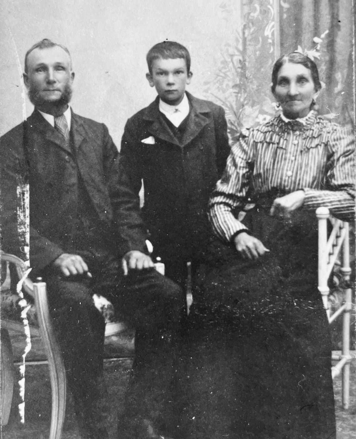 Porträtt på en man, en kvinna och ett barn. Fotot är taget i fotoateljé omkring 1910.