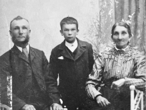 Porträtt på en man, en kvinna och ett barn. Fotot är taget i fotoateljé omkring 1910.
