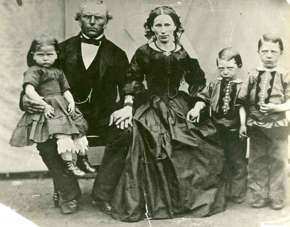 Ett familjefoto där endast kvinnan ser glad ut och de övriga visar upp sura miner.