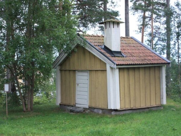 Stuga med skorsten en grönskande sommardag.