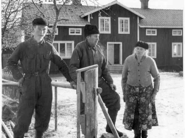 Tre människor står intill en gärdesgård som håller på att byggas.